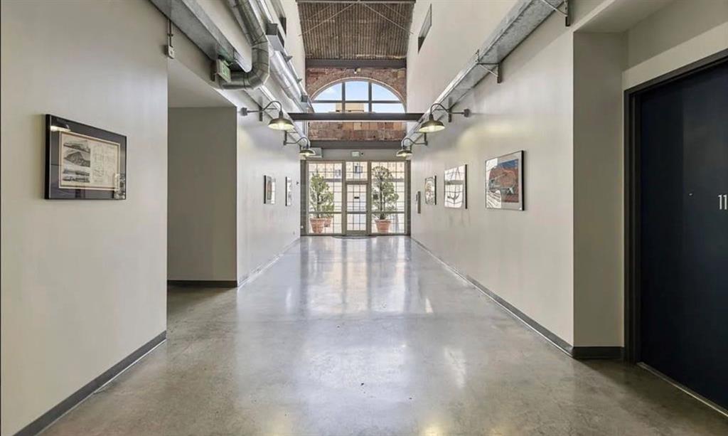 1122 Jackson Street, Unit 514 Dallas, TX 75202 - Photo 30 of 40 Industrial-inspired hallway featuring polished concrete flooring, exposed ceiling ducts, and a series of wall-mounted light fixtures