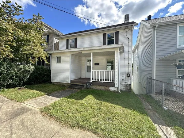 a view of a house with a yard and lawn chairs under an umbrella