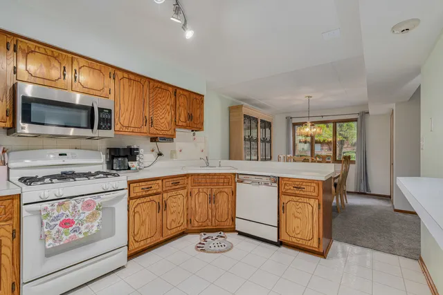 a kitchen with stainless steel appliances granite countertop a stove top oven a sink dishwasher and white cabinets with wooden floor
