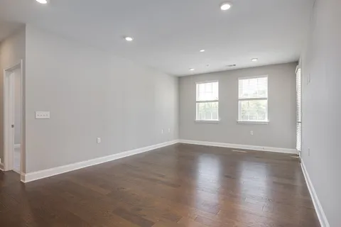 a view of an empty room with wooden floor and window