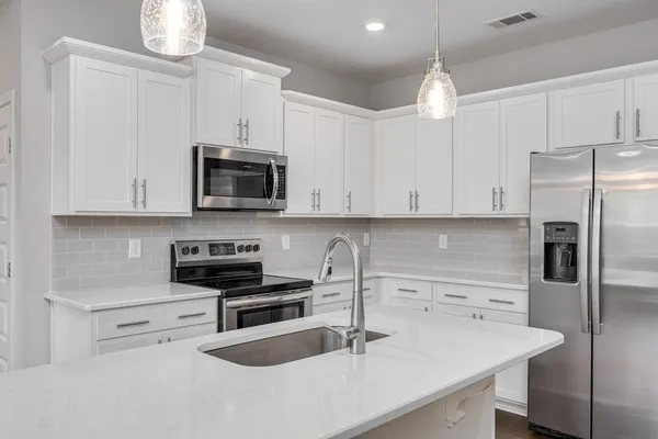 a kitchen with granite countertop a sink a stove and refrigerator