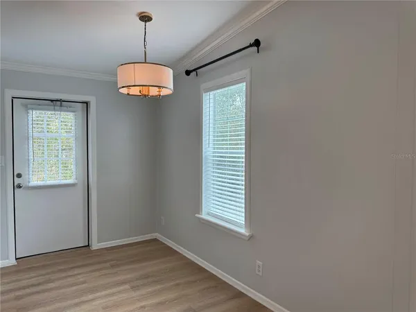 a view of an empty room with a window and wooden floor