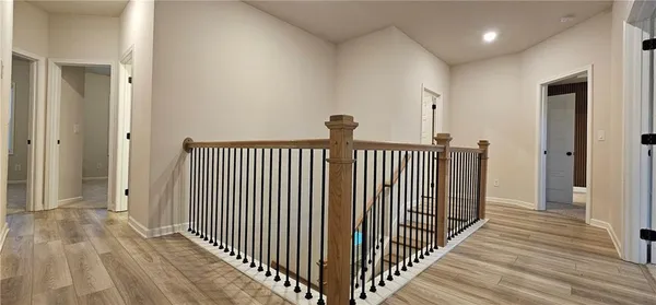 a view of a hallway with wooden floor and a bathroom