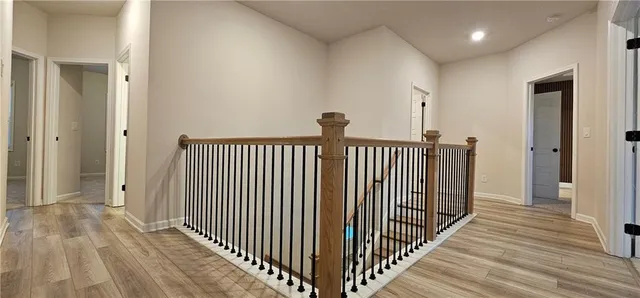 a view of a hallway with wooden floor and a bathroom