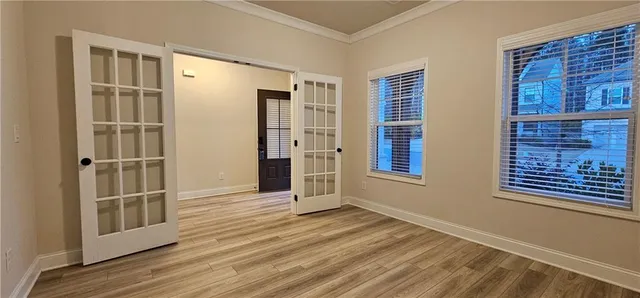 a view of an empty room with wooden floor and a window