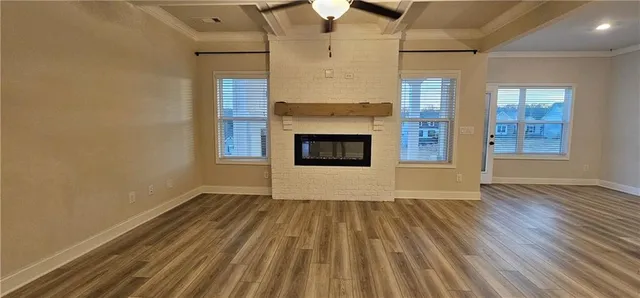 an empty room with wooden floor fireplace and windows