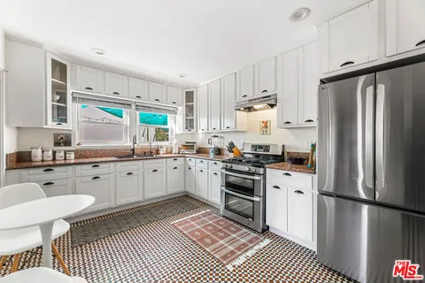 a kitchen with stainless steel appliances a refrigerator sink and white cabinets