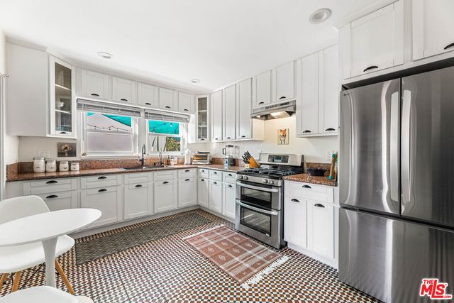 a kitchen with stainless steel appliances a refrigerator sink and white cabinets
