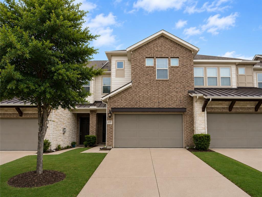 8235 Snapdragon Way Dallas, TX 75252 - Photo 1 of 29 Contemporary townhouse facade featuring a two-car garage, brick and stone veneer, and a metal roof awning