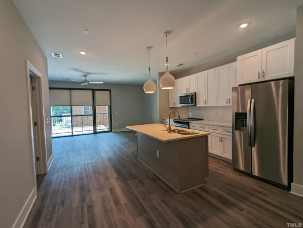 a large kitchen with a wooden floor and a refrigerator