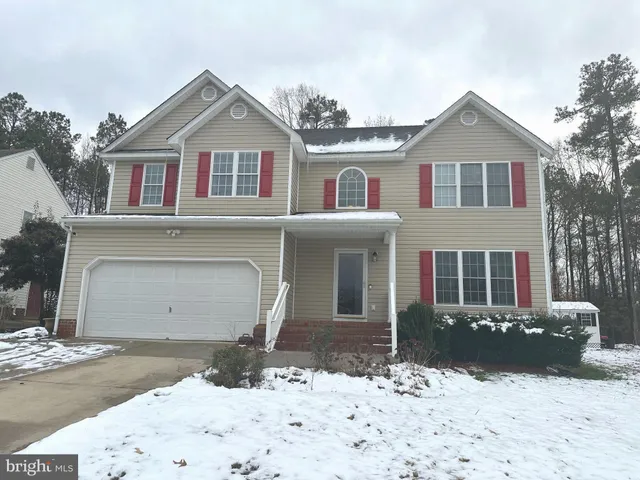 a front view of a house with a yard covered in snow