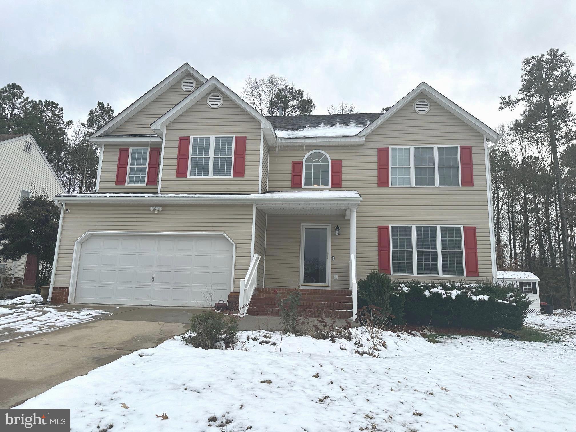 a front view of a house with a yard covered in snow