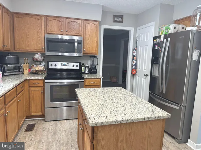 a kitchen with granite countertop a refrigerator and a sink