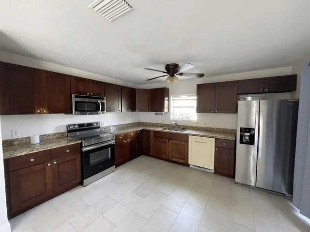a large kitchen with stainless steel appliances granite countertop a stove cabinets and a sink