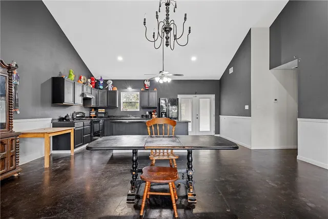 a kitchen with stainless steel appliances kitchen island granite countertop a stove top oven a sink a dining table and chairs with wooden floor