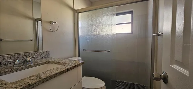 a bathroom with a granite countertop sink toilet and shower