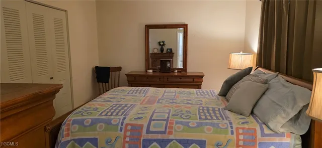 a bedroom with a bed and a lamp on dresser