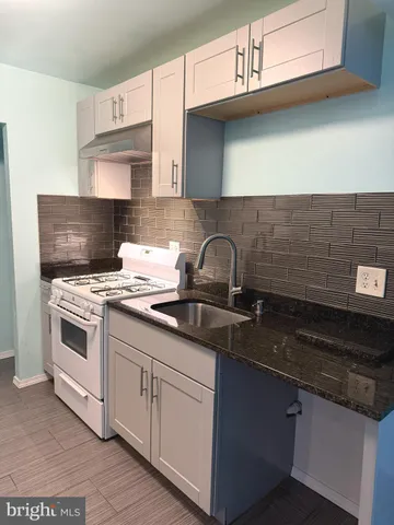 a kitchen with granite countertop a sink stove and cabinets