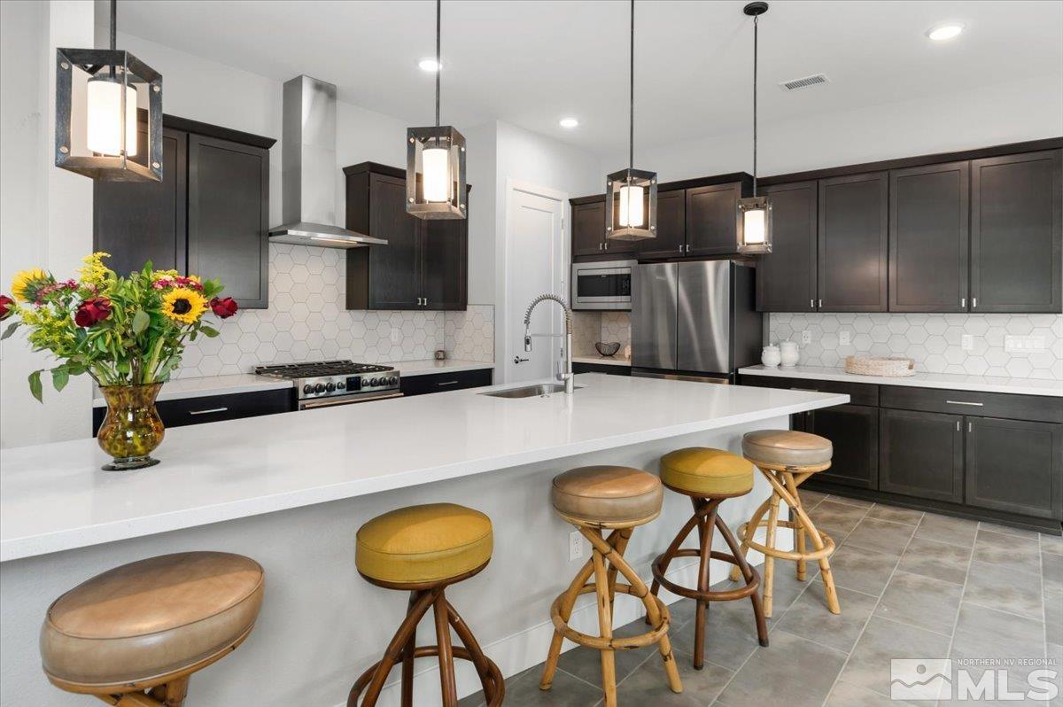 8773 Larkhaven Trail Reno, NV 89523 - Photo 9 of 38 a kitchen with stainless steel appliances granite countertop a sink chairs and refrigerator