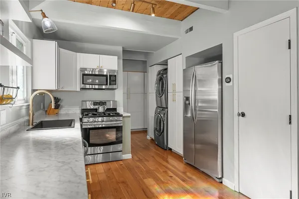 a kitchen with stainless steel appliances granite countertop a refrigerator a stove and a sink