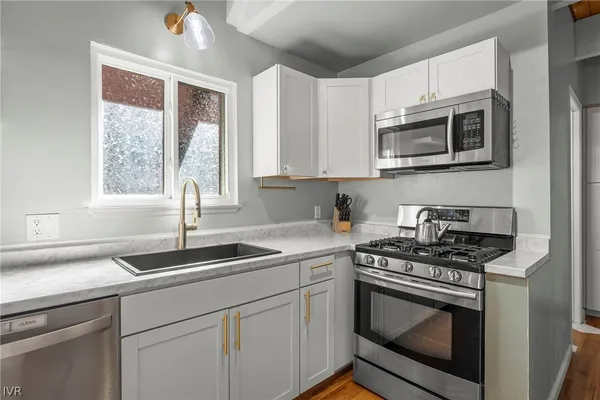 a kitchen with stainless steel appliances granite countertop white cabinets granite counter tops and a window
