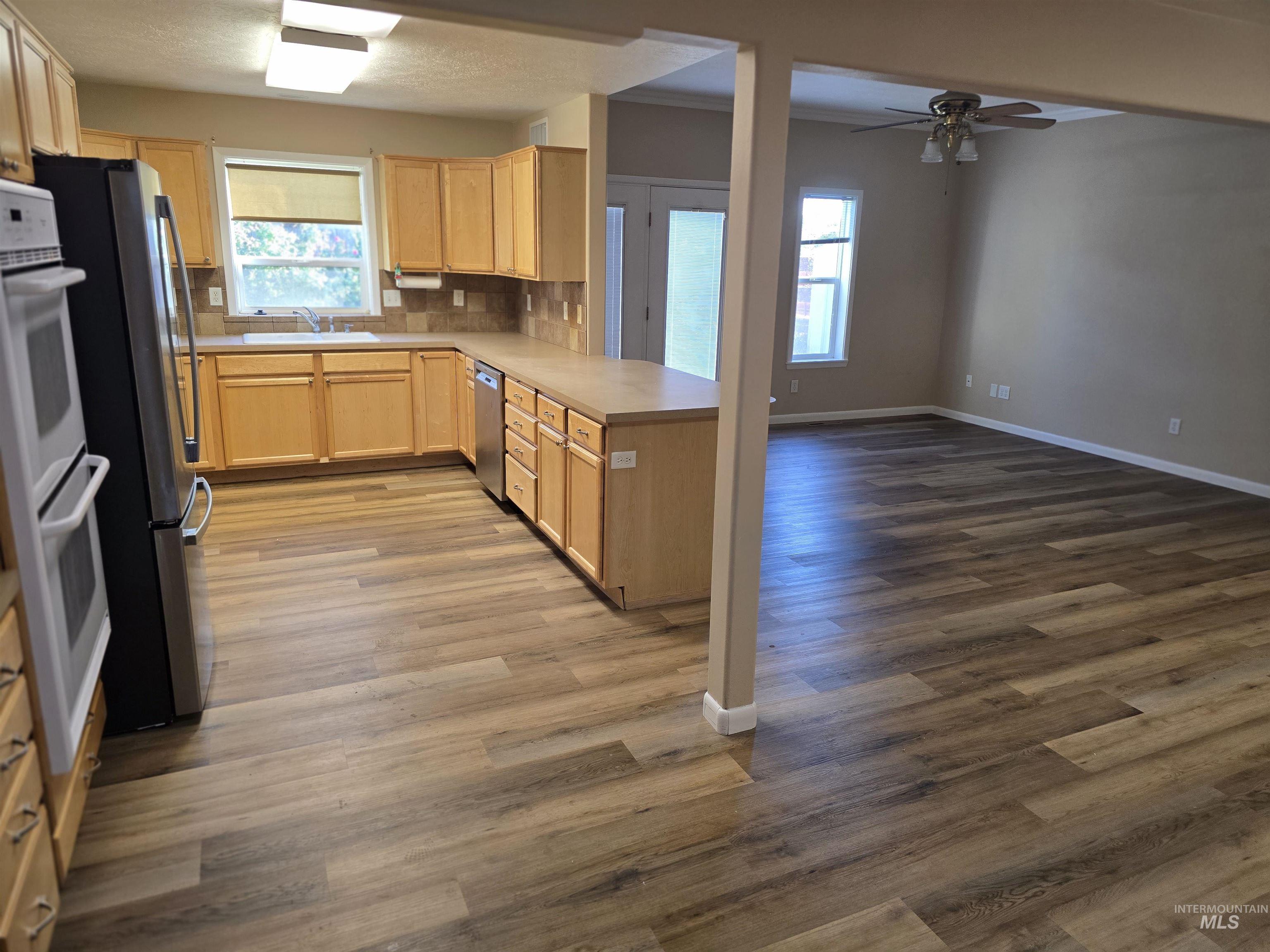1818 Granada Drive Twin Falls, ID 83301 - Photo 6 of 16 Kitchen featuring light brown cabinetry, appliances with stainless steel finishes, a ceiling fan, a peninsula, and dark wood-style flooring