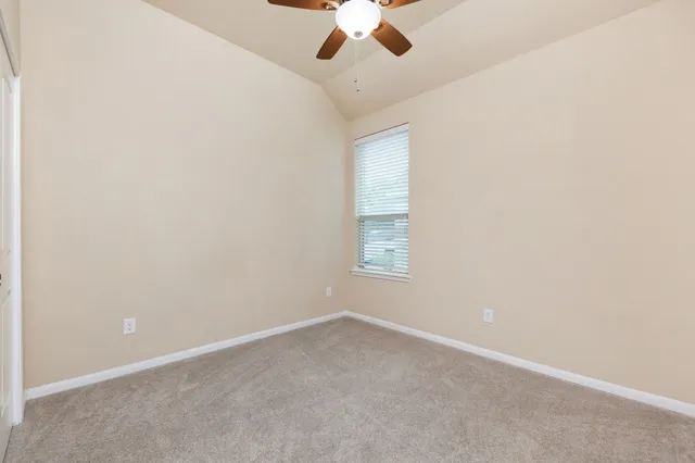 an empty room with a ceiling fan and window