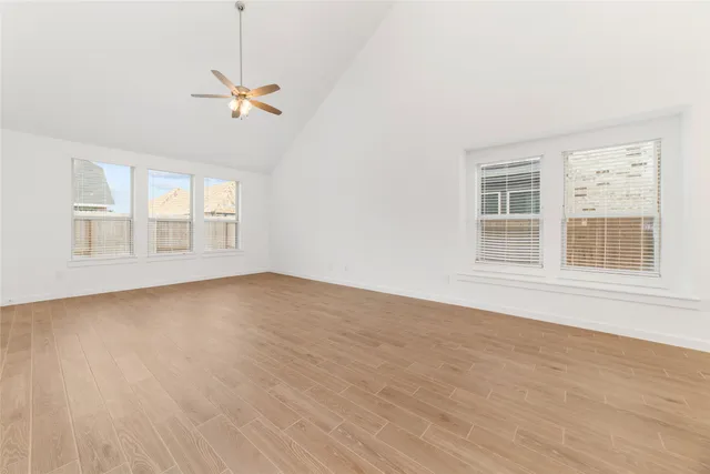 a view of a big room with wooden floor and windows