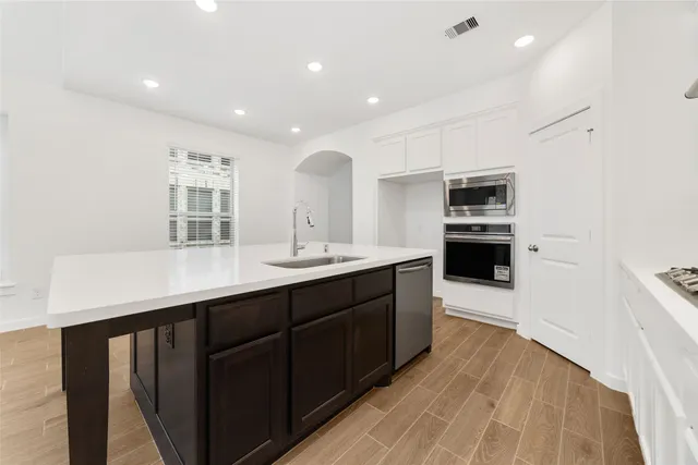 a large kitchen with stainless steel appliances a sink dishwasher stove and oven