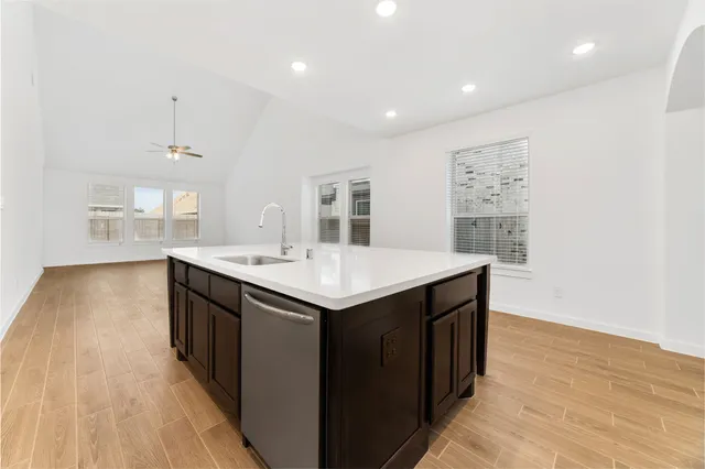 a living room with stainless steel appliances kitchen island a table chairs in it and a window