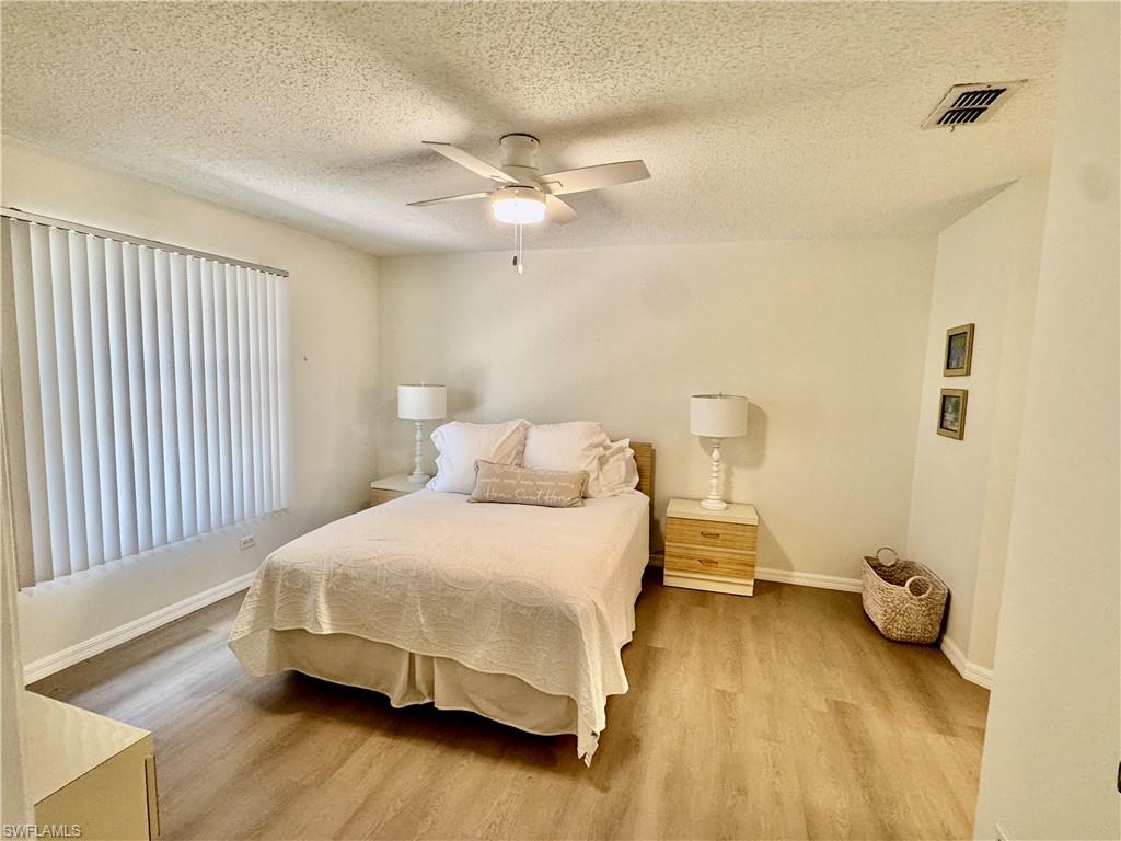 645 Squire Court, Unit 202 Naples, FL 34104 - Photo 25 of 41 a bedroom with a bed and wooden floor