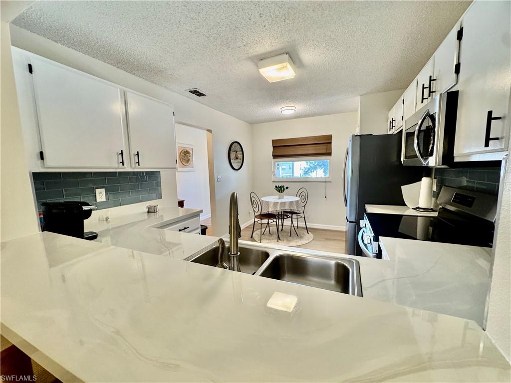 645 Squire Court, Unit 202 Naples, FL 34104 - Photo 30 of 41 a kitchen with stainless steel appliances kitchen island granite countertop a sink a stove and white cabinets
