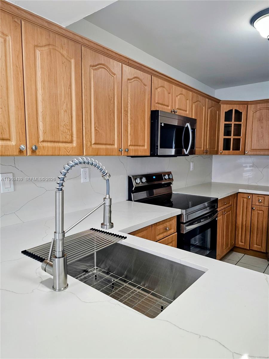15581 Southwest 144th Court Miami, FL 33177 - Photo 20 of 37 a kitchen with stainless steel appliances granite countertop a stove a sink and a microwave