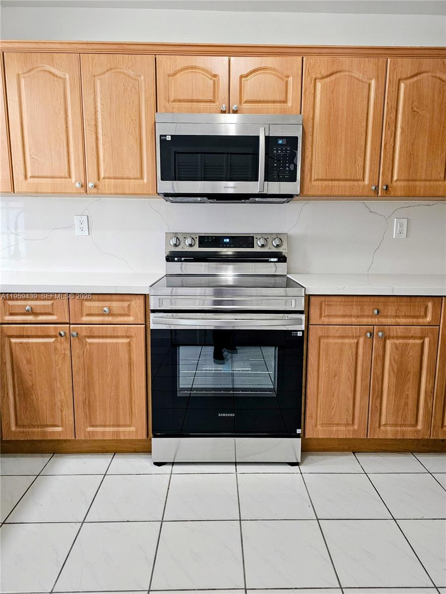 15581 Southwest 144th Court Miami, FL 33177 - Photo 21 of 37 a kitchen with granite countertop a stove top oven microwave and cabinets