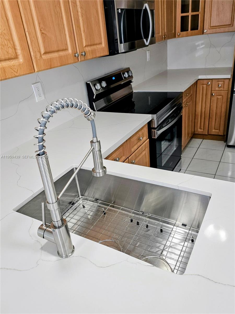15581 Southwest 144th Court Miami, FL 33177 - Photo 22 of 37 a kitchen with a sink a stove and cabinets