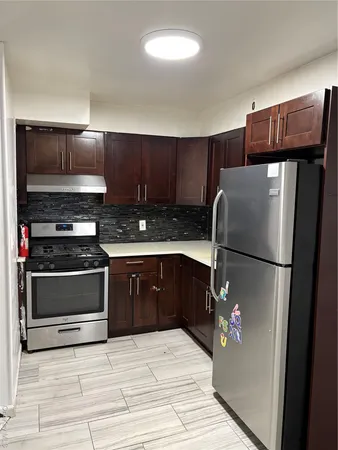 a kitchen with stainless steel appliances granite countertop a refrigerator a stove and a sink with wooden cabinets