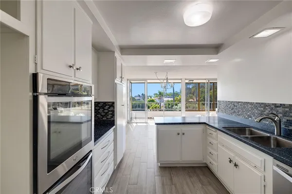 a kitchen with stainless steel appliances white cabinets and wooden floor