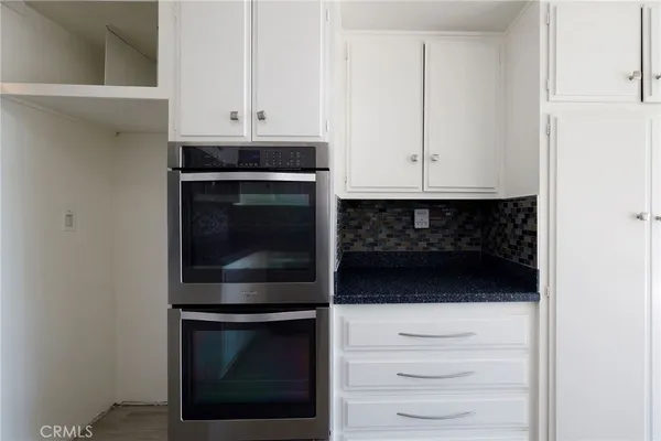 a kitchen with granite countertop white cabinets and stainless steel appliances