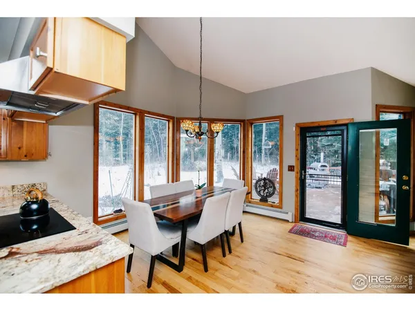 a kitchen with stainless steel appliances granite countertop a stove top oven a sink dishwasher a dining table and chairs with wooden floor