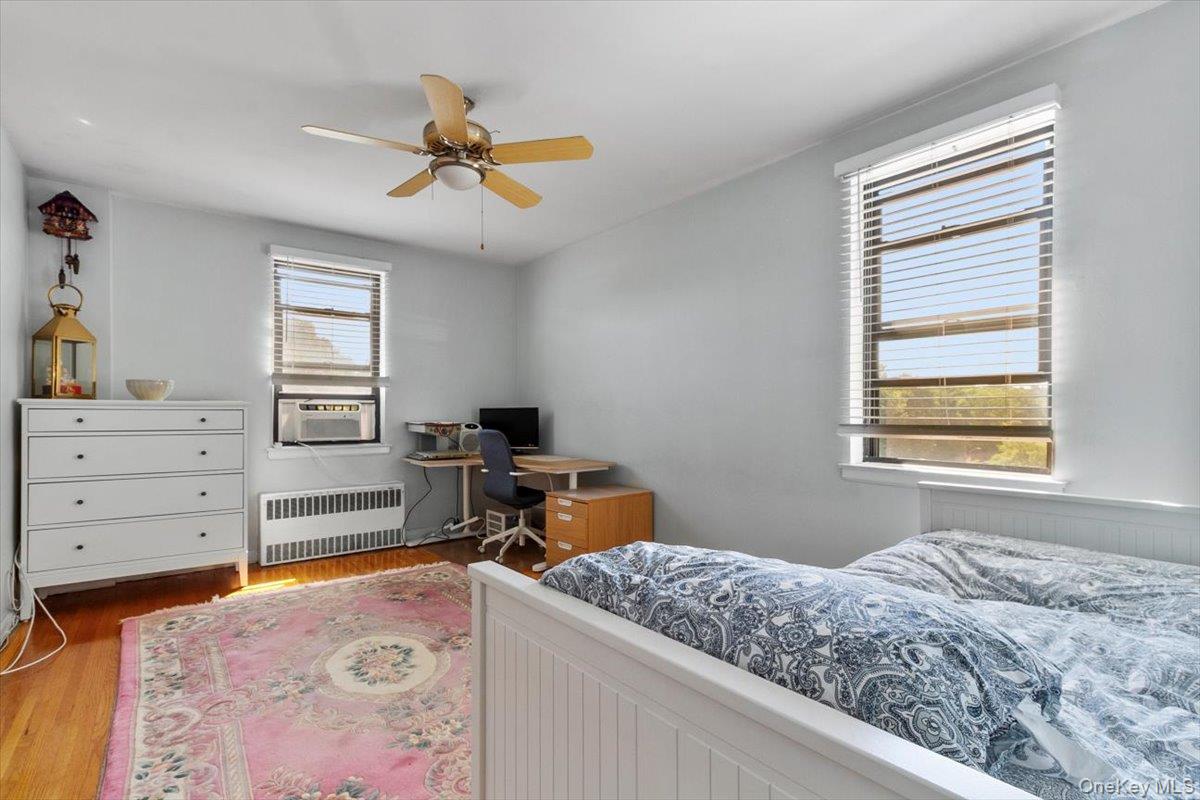 142 Garth Road, Unit 2H Scarsdale, NY 10583 - Photo 11 of 14 Bedroom with wood finished floors, radiator heating unit, a ceiling fan, and a desk