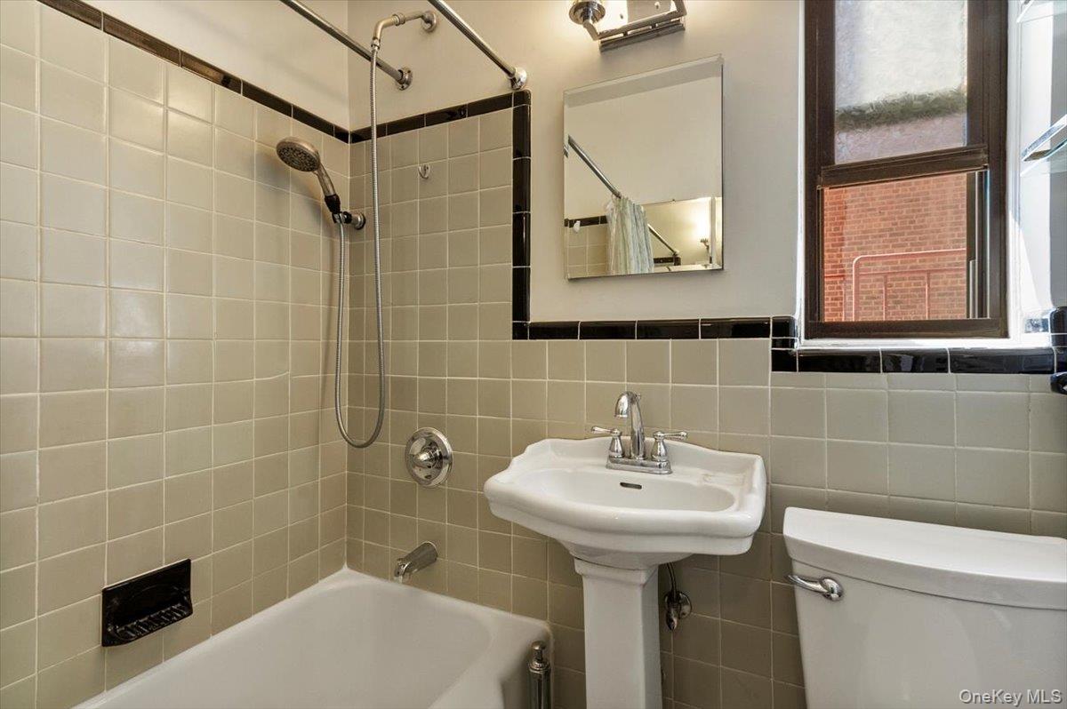 142 Garth Road, Unit 2H Scarsdale, NY 10583 - Photo 12 of 14 Bathroom with shower / bath combo, tile walls, and decorative backsplash