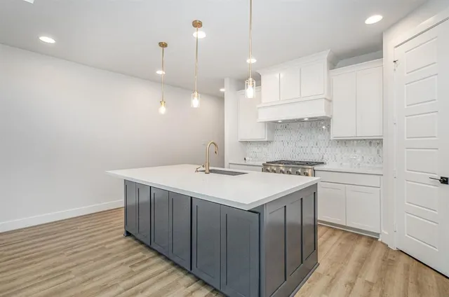 a kitchen with a sink a stove a refrigerator and white cabinets with wooden floor