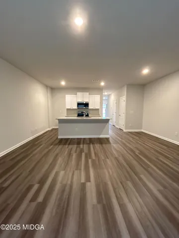 a view of kitchen and empty room with wooden floor