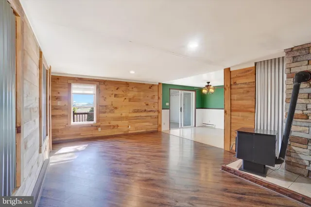a view of an empty room with wooden floor and a kitchen