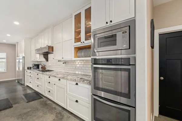 a kitchen with granite countertop white cabinets and stainless steel appliances
