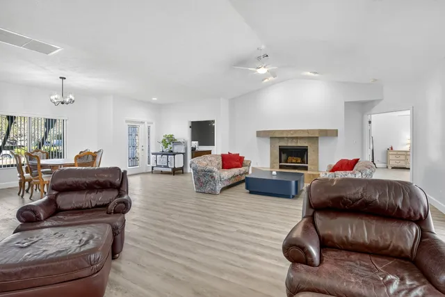 a kitchen with stainless steel appliances kitchen island granite countertop a stove a sink a refrigerator and white cabinets with wooden floor