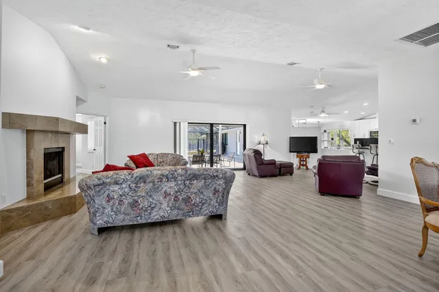 a living room with furniture kitchen area and a wooden floor
