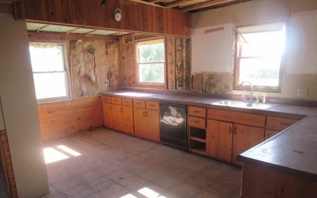 a large kitchen with granite countertop a sink window and cabinets