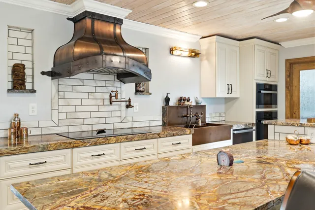 a kitchen with a stove a sink dishwasher and white cabinets with wooden floor