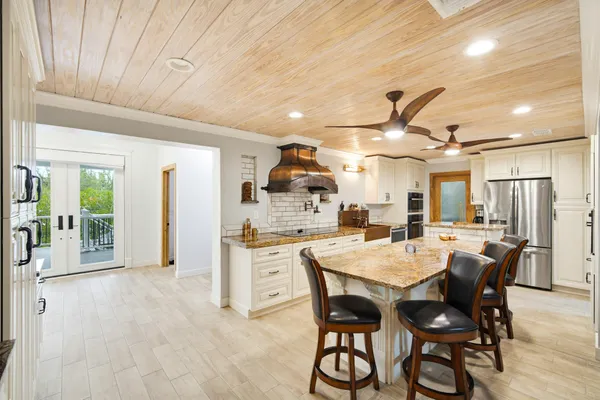 a kitchen with stainless steel appliances kitchen island granite countertop a stove a sink and a white cabinets